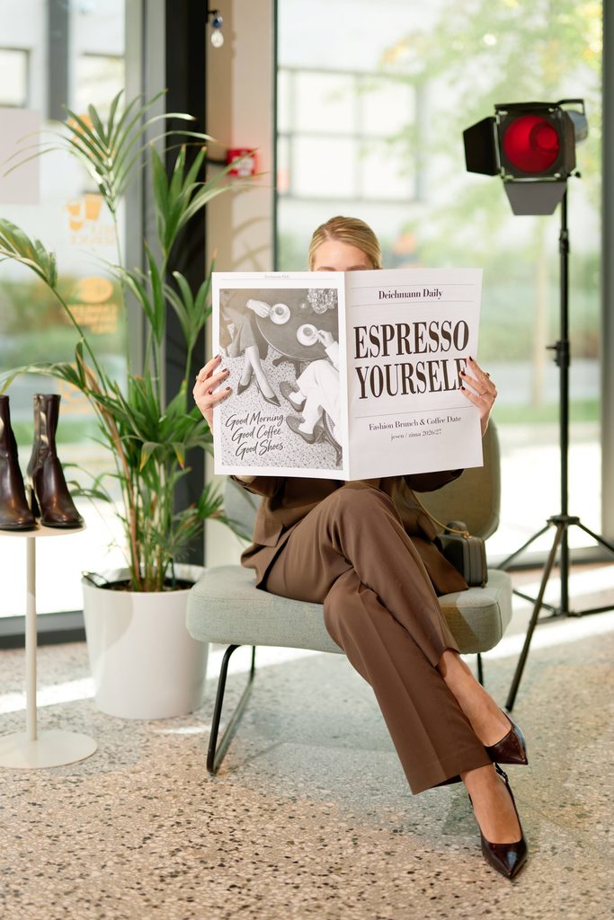 Gošća na predstavljanju Deichmann kolekcije jesen/zima 2026/2027 drži novine sa natpisom Espresso Yourself.