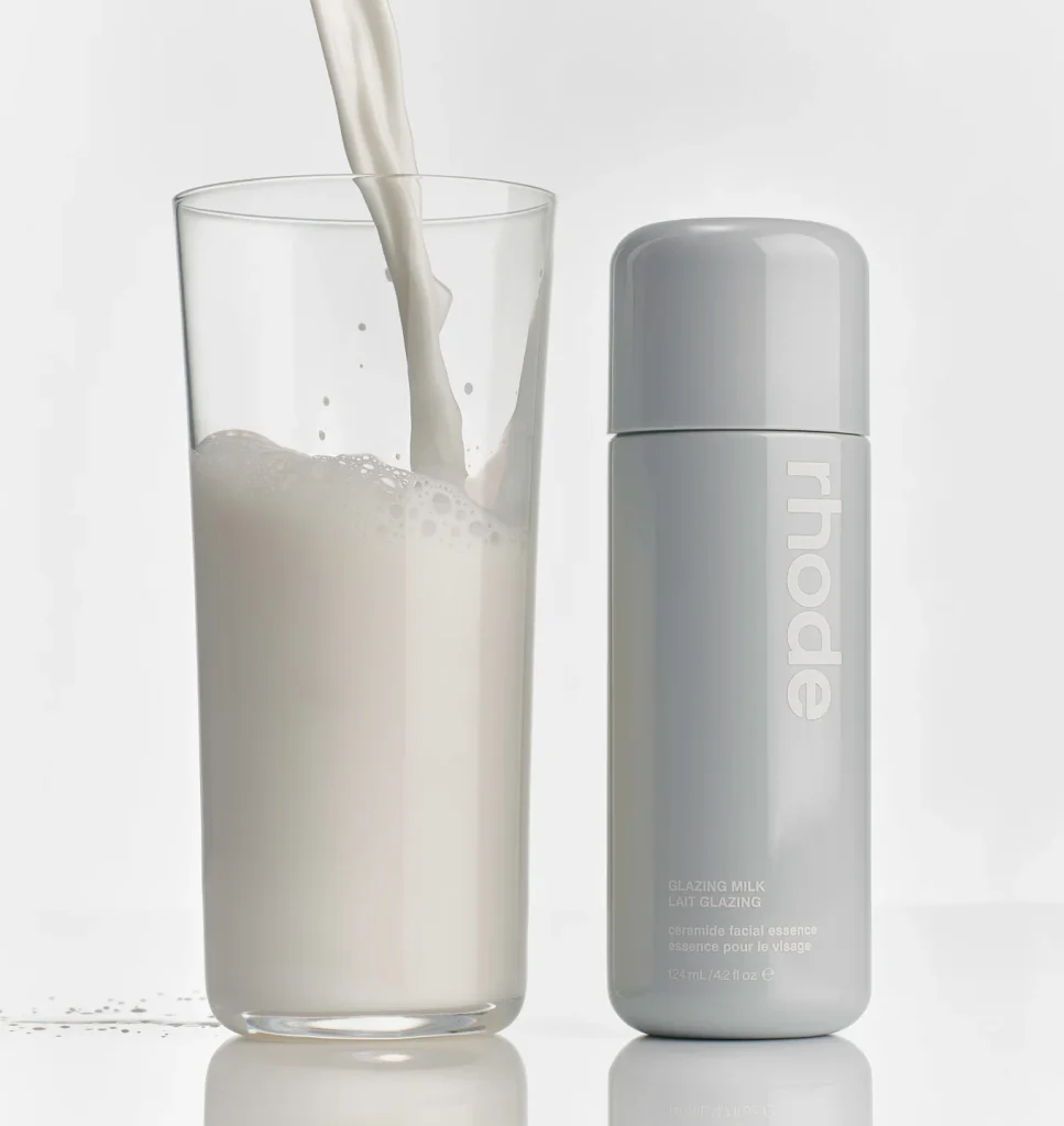 Rhode Glazing Milk mlečna esencija pored čaše u koju se sipa mleko.
