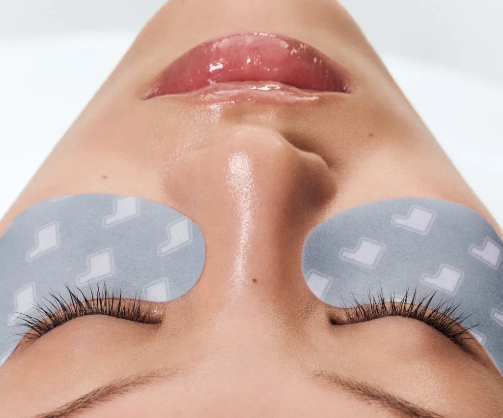 Krupni plan lica devojke sa Rhode Peptide Eye Prep hidrogel maskicama za područje ispod očiju.